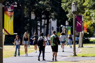 Students walk outside on a sunny day on Northeastern's Oakland campus.