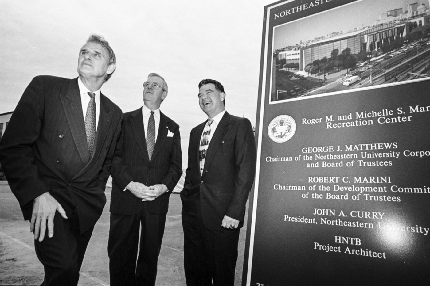 Three individuals, including George Matthews, stand in front of a black poster with white text that reads "Roger M. and Michelle S. Marino Recreation Center."