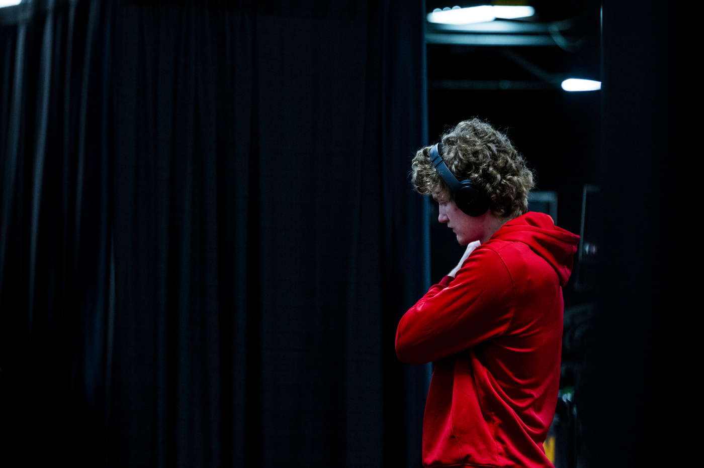 Person wearing a red hoodie and headphones with their arms crossed. 