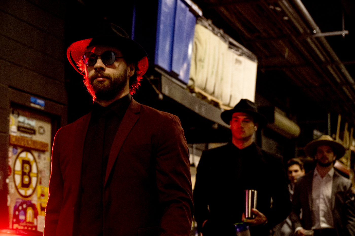 Men's hockey players wearing suits and hats walk into TD Garden in a line.