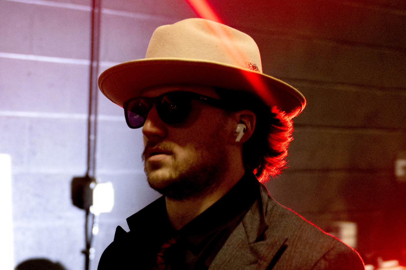 Men's hockey player wearing a felt hat, sunglasses, and AirPods as he enters TD Garden.