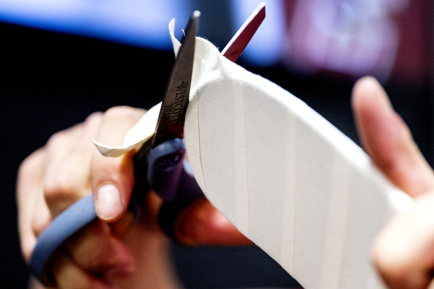 Person using scissors to cut the tape around a hockey stick.