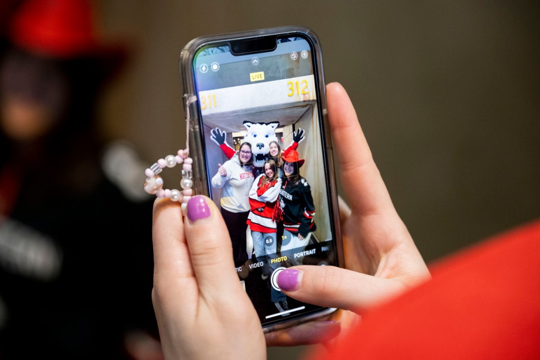 A person with purple nail polish taking an iPhone photo of a group of friends posing with Paws.