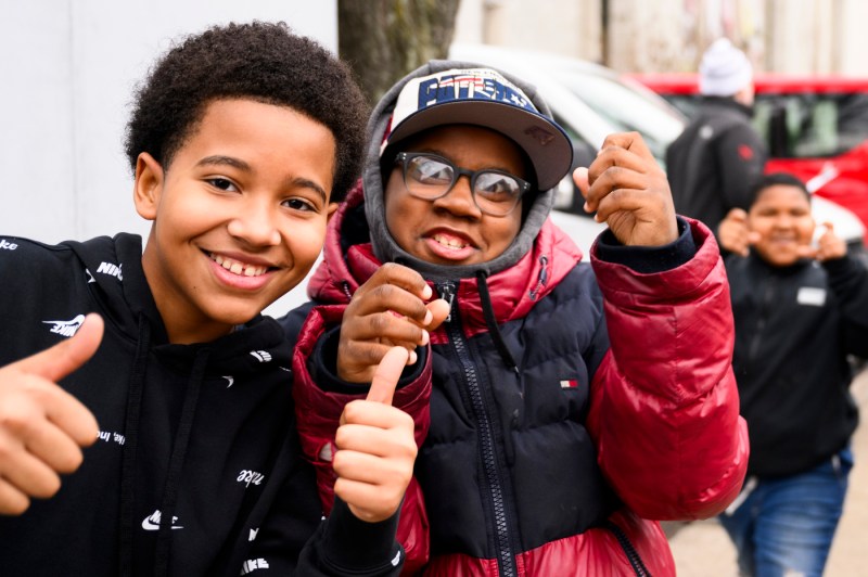 Kids smiling and holding thumbs up for the camera. 