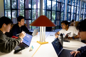 Four people sit around a table inside a library.