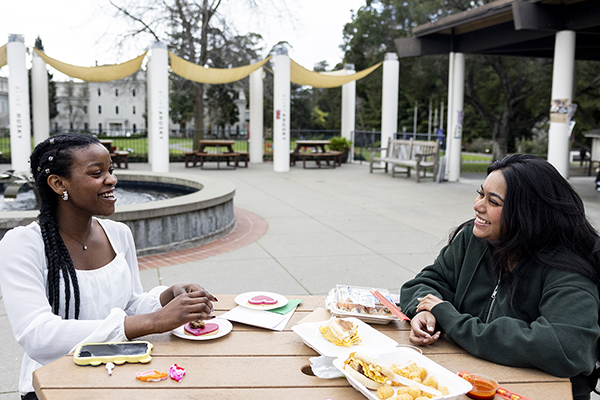 Two people eat lunch outside on a cloudy day.