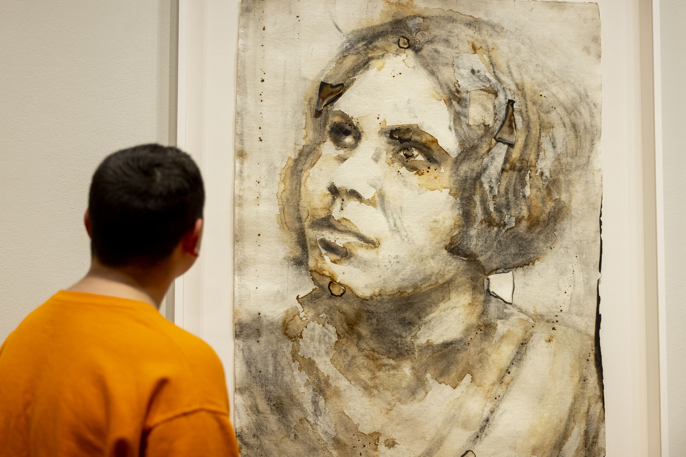 A child name John looking at a piece of artwork by Monica Lundy that features a woman looking upwards.