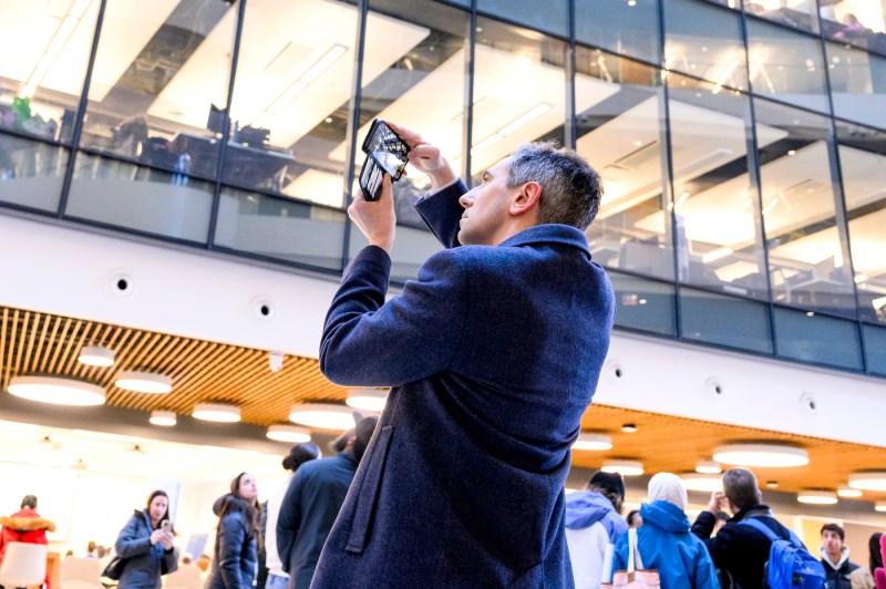 A person takes a picture with their phone inside a brightly lit lobby.