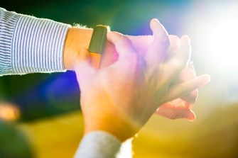 A hand adjusts a smartwatch-looking device on an outstretched arm