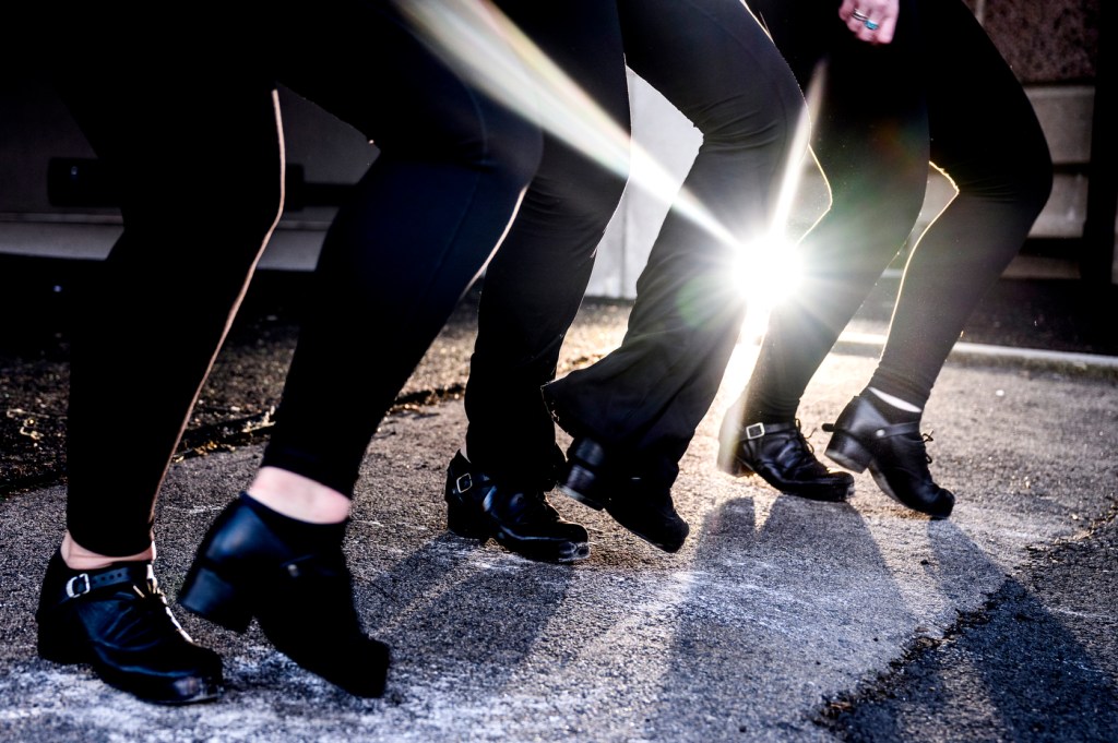 Three people dance while wearing heavies and black leggings.