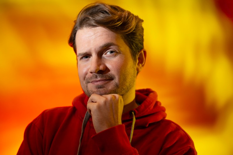 Alexander Sharp posing with a hand under his chin and an eyebrow raised.