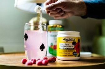 A hand pours pink-colored powdered magnesium into a cup.