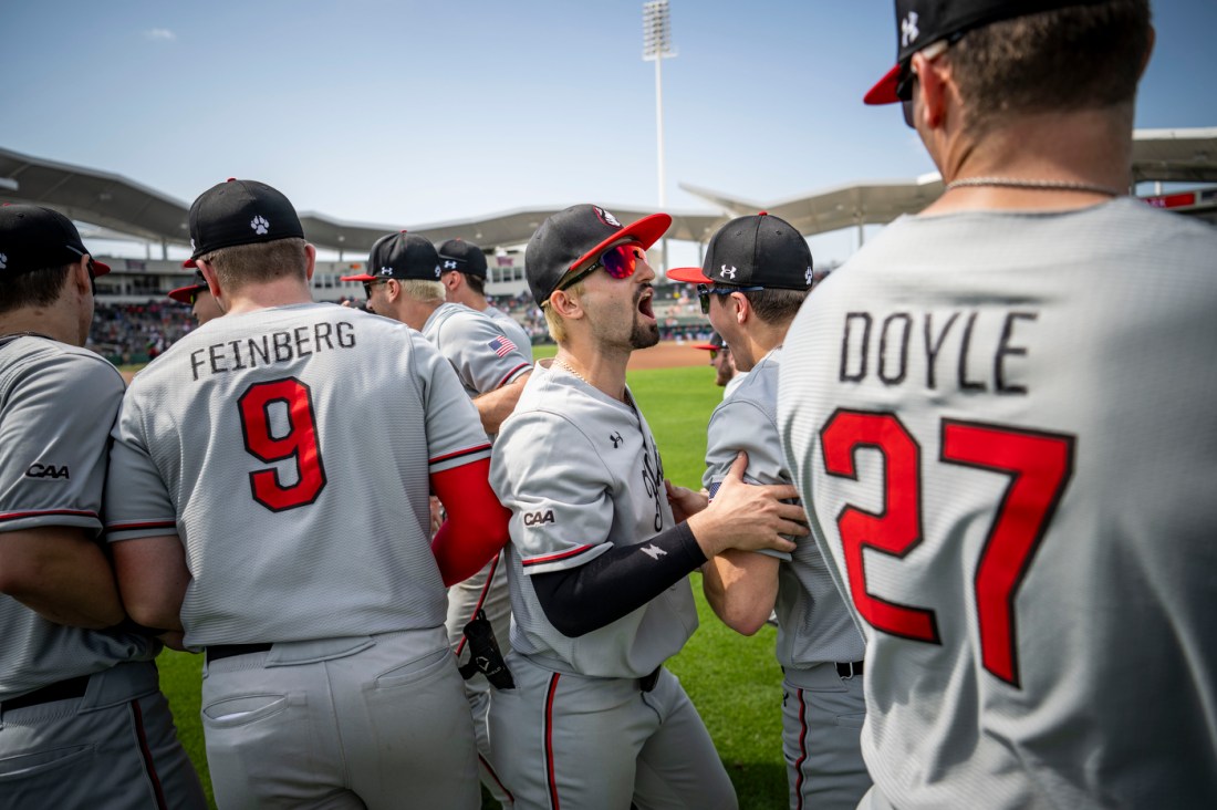 Seven baseball players wearing grey uniforms with red numbers stand together outside on a baseball field before facing off against the Boston Red Sox.