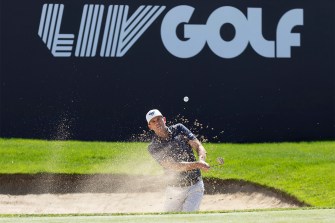 A golfer hits a gold ball out of a sand pit during a tournament in Saudi Arabia.