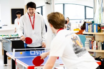 Two people wearing white play table tennis together.