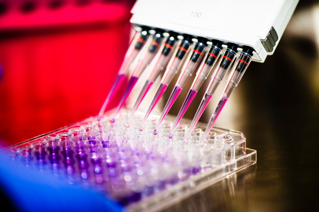 A white-colored device injects a liquid into test tubes.