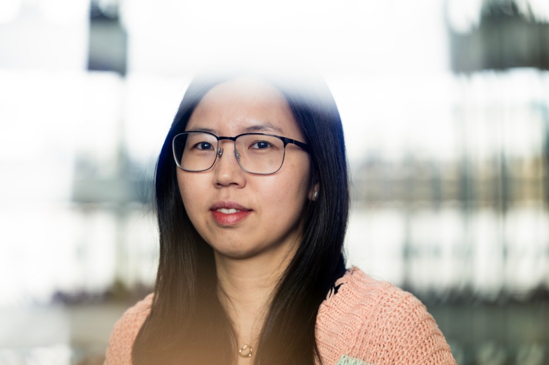 A woman with dark hair, glasses and a sweater poses for a portrait.