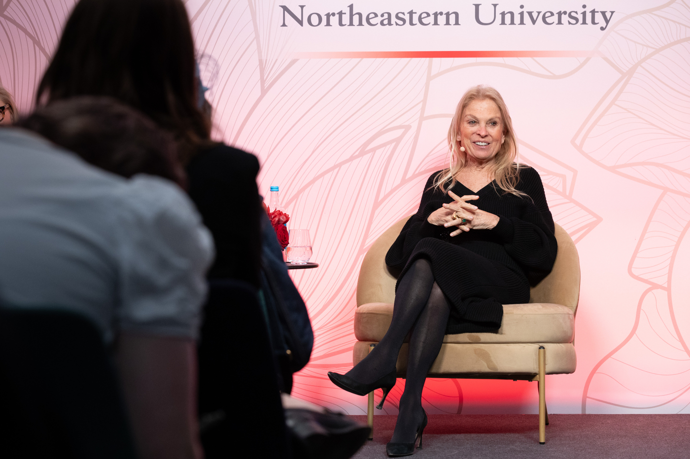 Jane D. Hartley sitting in a brown velvet chair at a Women Who Empower event in the UK.