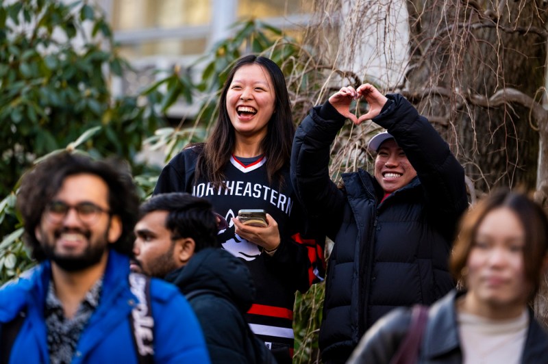 Audience members smiling and making heart shapes with their hands.