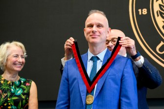 Joseph Aoun putting a medal around David De Cremer's neck.