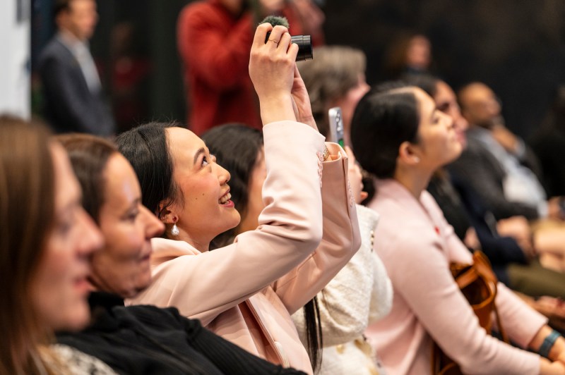 Audience member taking a photo on a point and shoot camera.