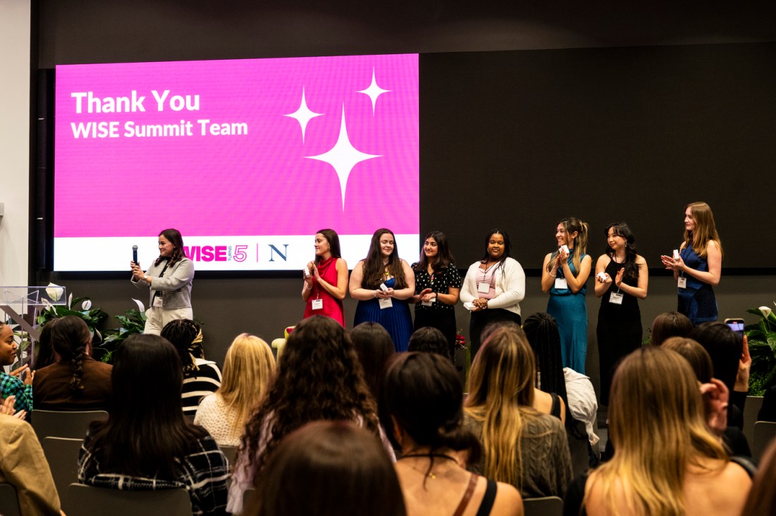 8 women standing on stage clapping at WISE Summit.