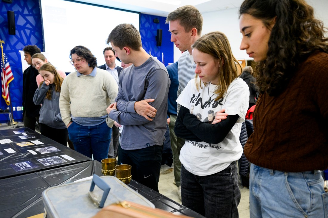 Audience members look at the memorabilia of a Holocaust survivor. 