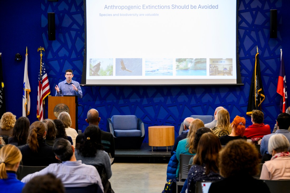 Ronald Sandler speaking on stage in front of a PowerPoint slide titled 'Anthropogenic Extinctions Should be Avoided'.