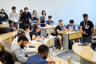 Students sitting in a room working on product pitches.