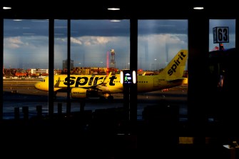 A spirit airplane on the tarmac outside of an airport.