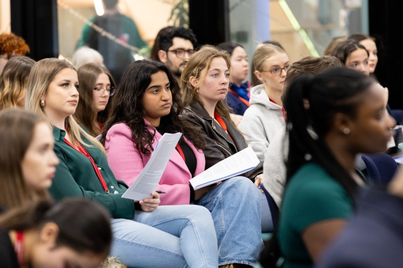 Audience members listening to a conference about law and AI.