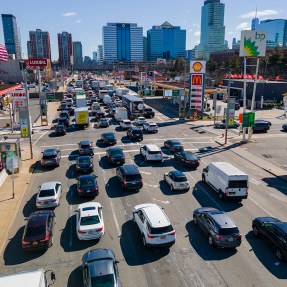 Dozens are cars in standstill traffic in a city on a sunny day.