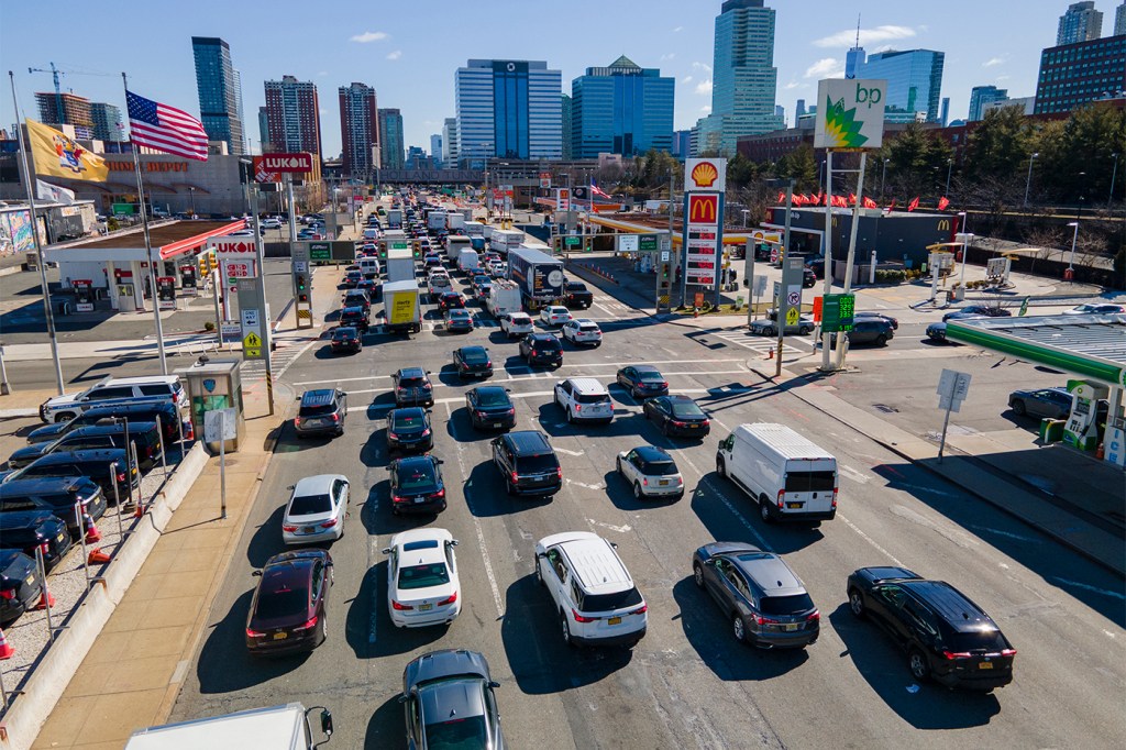 Dozens are cars in standstill traffic in a city on a sunny day.