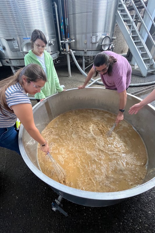 Grace Arents helping stir a large vat.