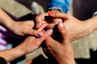 A group of people all holding their hands clasped together.