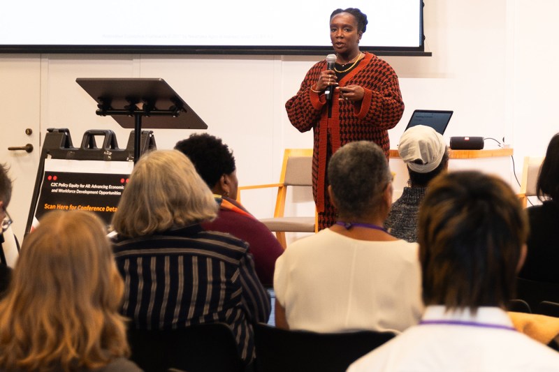 A person speaking into a microphone to an audience.