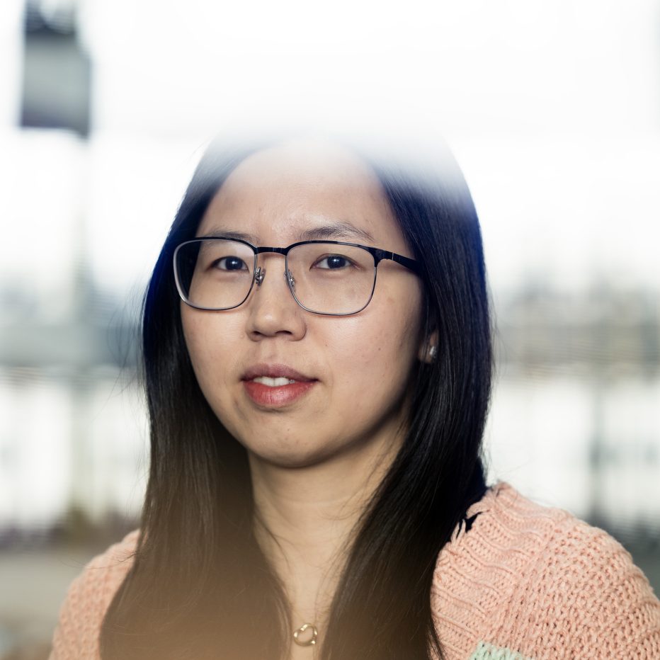 A woman with dark hair, glasses and a sweater poses for a portrait.