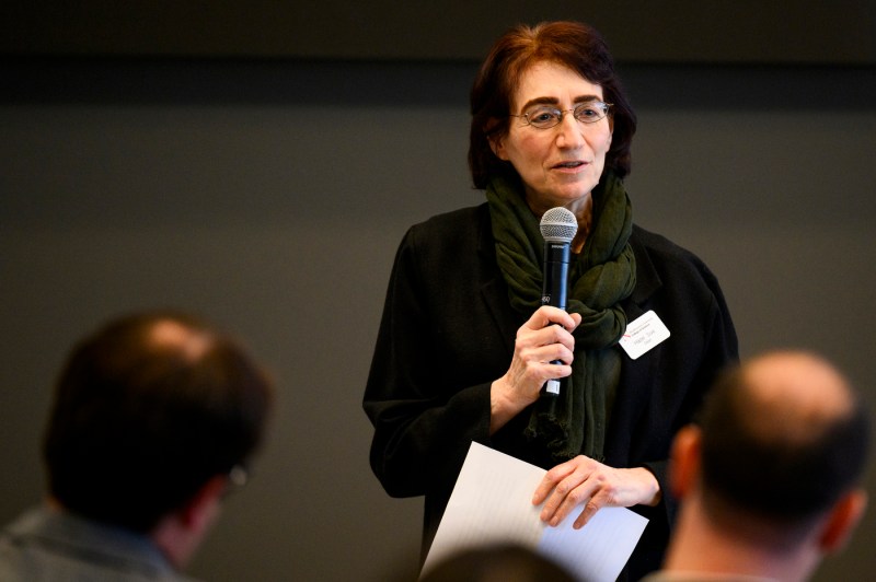 A person speaking into a microphone at the event with Francis Collins and Dave DeSteno.