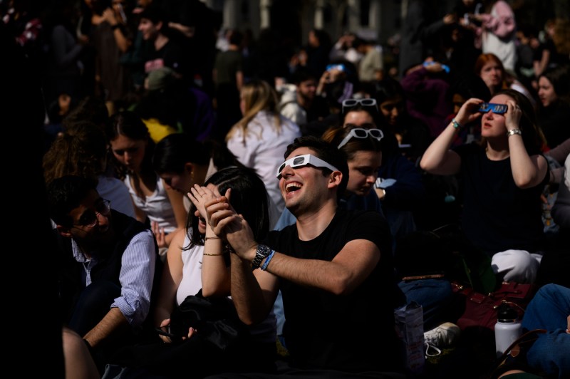 Students looking up at the sun wearing solar eclipse glasses. 