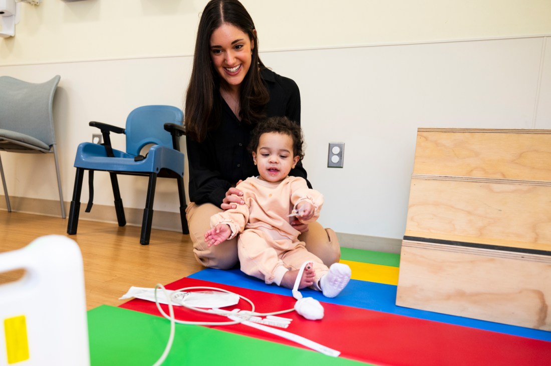 Isabella Rando sitting on the floor with a child. 