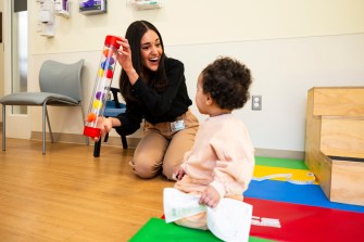 Isabella Rando playing on the floor with a child.