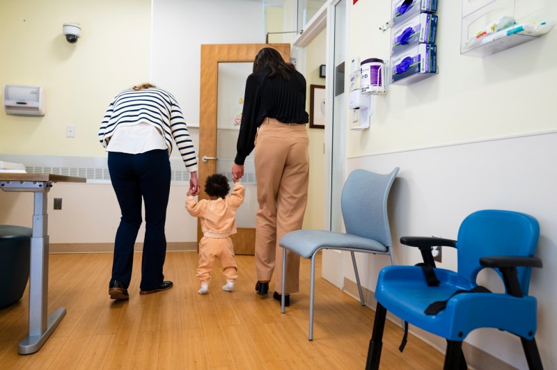 Isabella RAndo and another woman each holding a child's hands and helping them walk. 