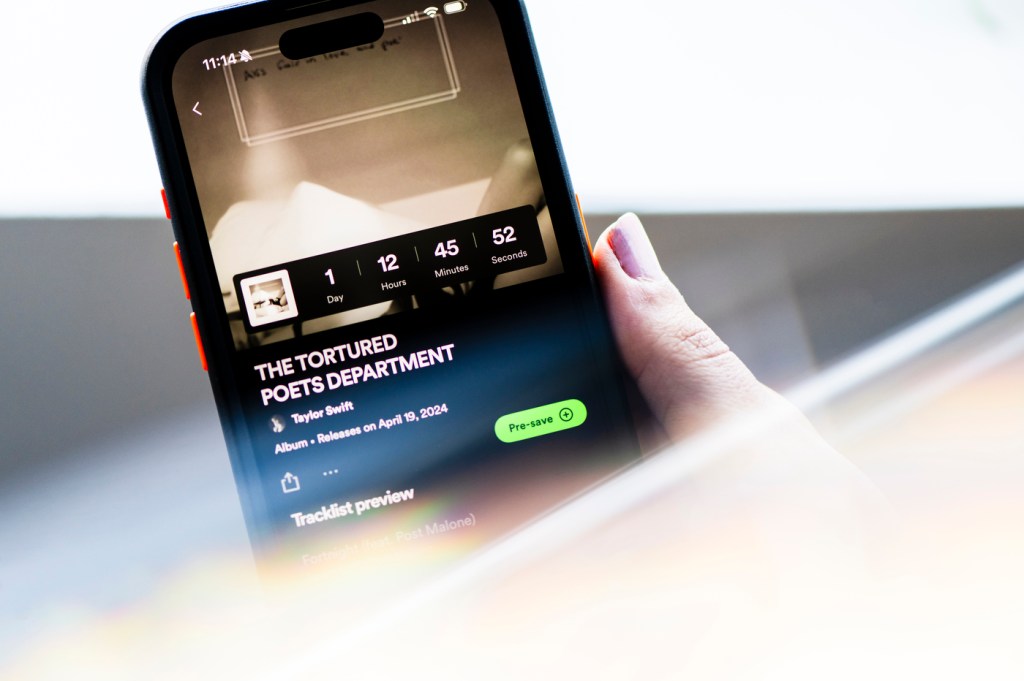 A person holding their iPhone open to The Tortured Poets Department pre-save album page on Spotify.
