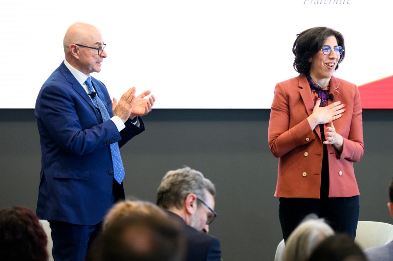 President Joseph E Aoun clapping on stage for Rima Abdul Malak who stands next to him with one hand over her heart.