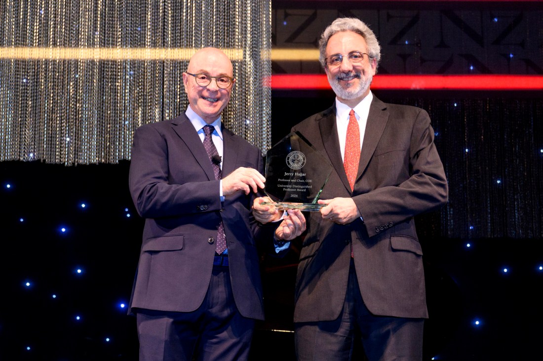 President Joseph Aoun posing with Jerome Hajjar while holding a glass award.