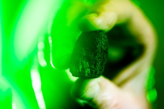 Robert Lowndes holding up a moon rock in green lighting.