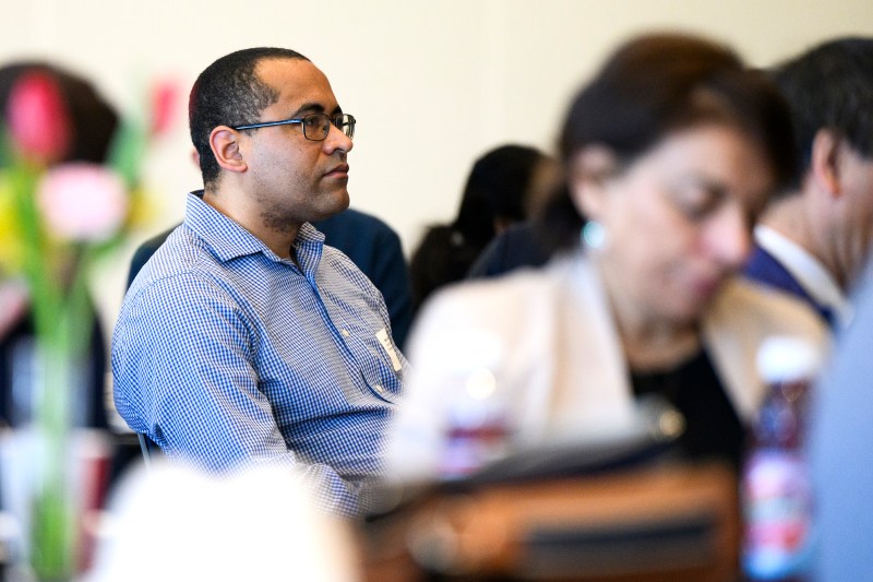 An audience member wearing a blue and white checked button down and glasses listening at the NanoSI launch event.