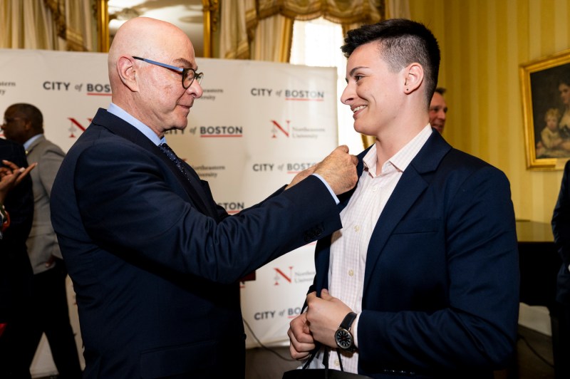 President Joseph Aoun puts a Northeatern Alumni pin on the lapels of a Moakley scholar.