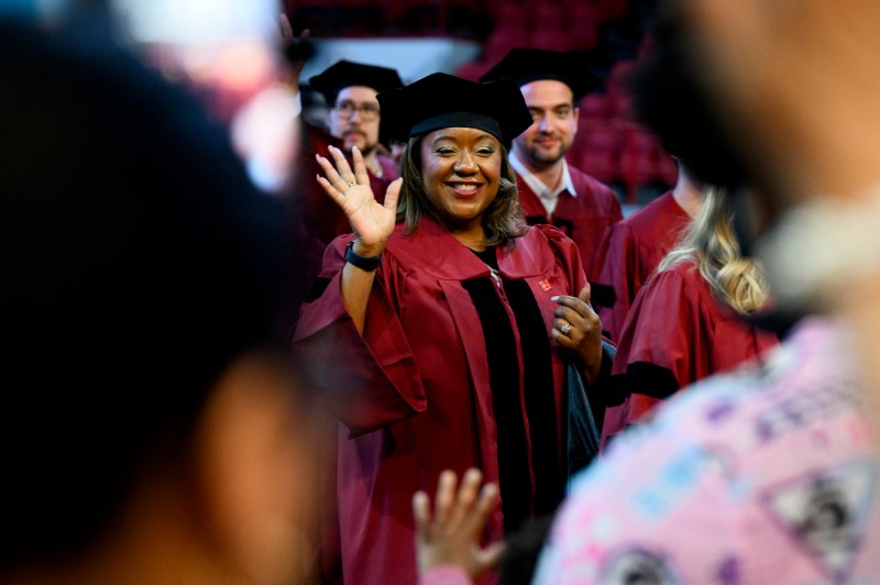 A graduate waving at the Doctor of Philosophy Hooding.