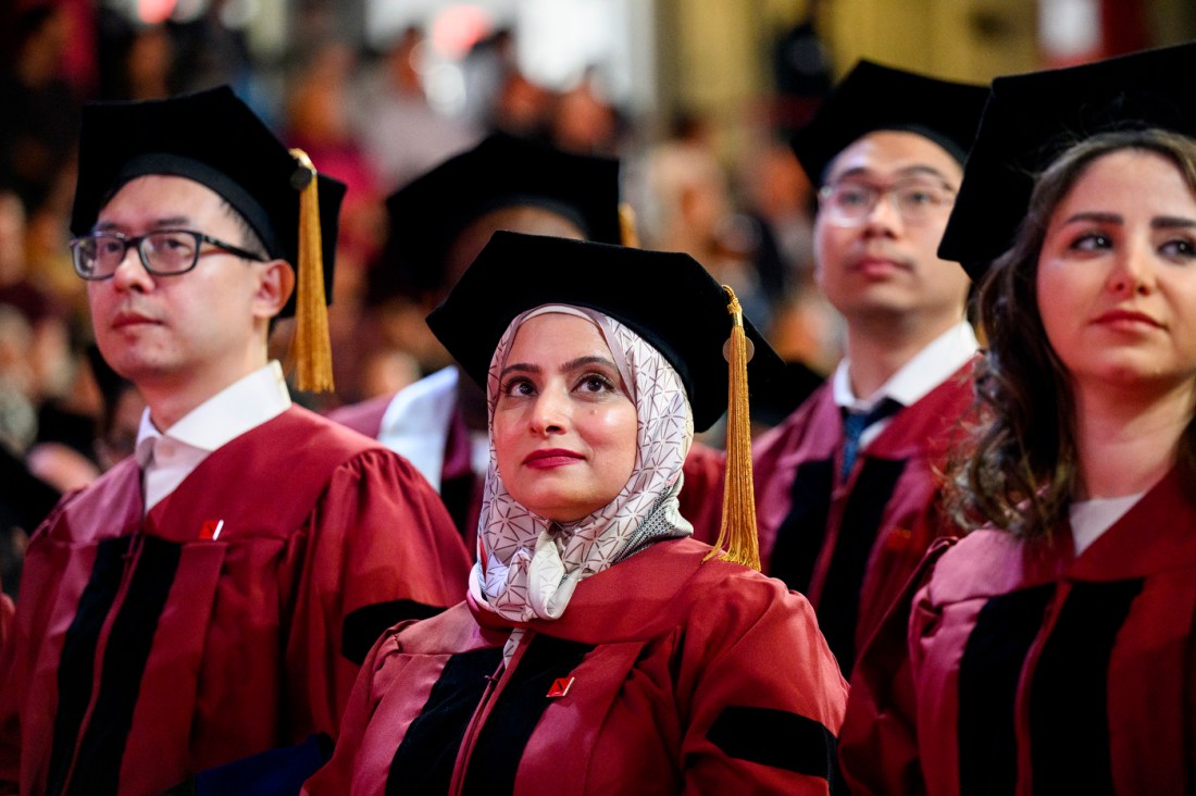 Graduates looking up on stage at the Doctor of Philosophy Hooding.